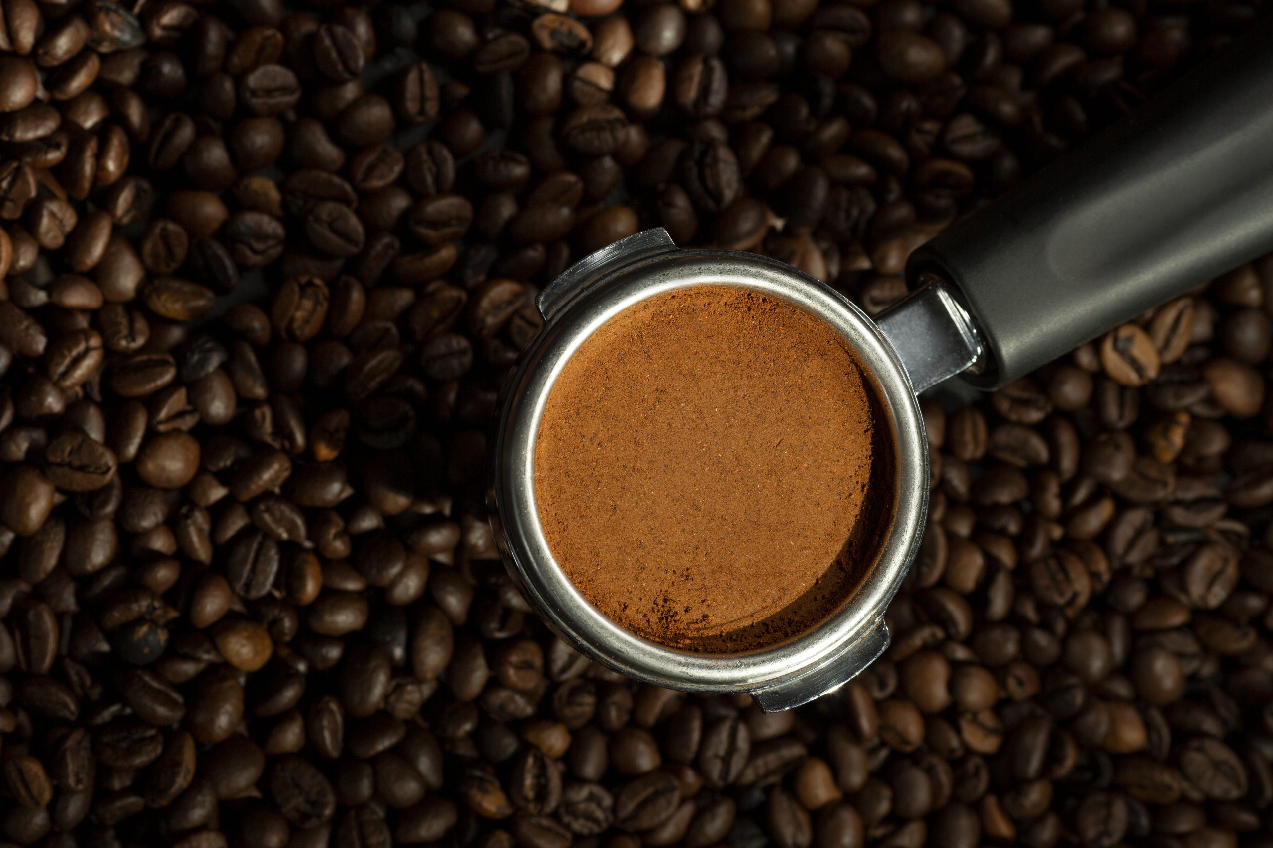 Espresso ground in brew cup over whole coffee beans